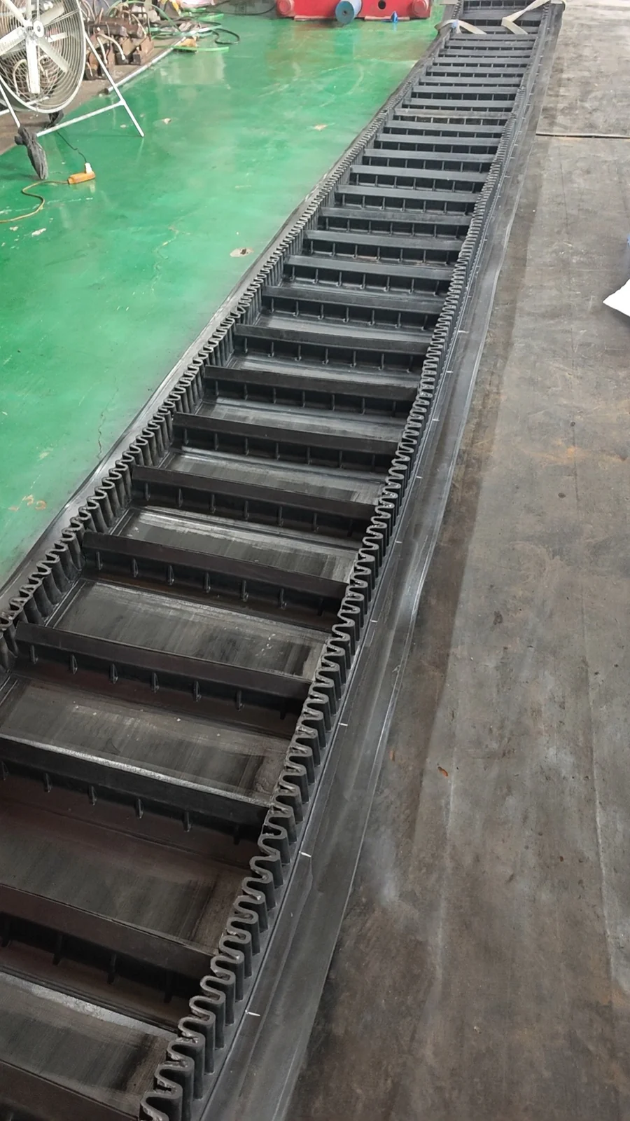 Corrugated sidewall conveyor belt with transverse cleats on the factory floor